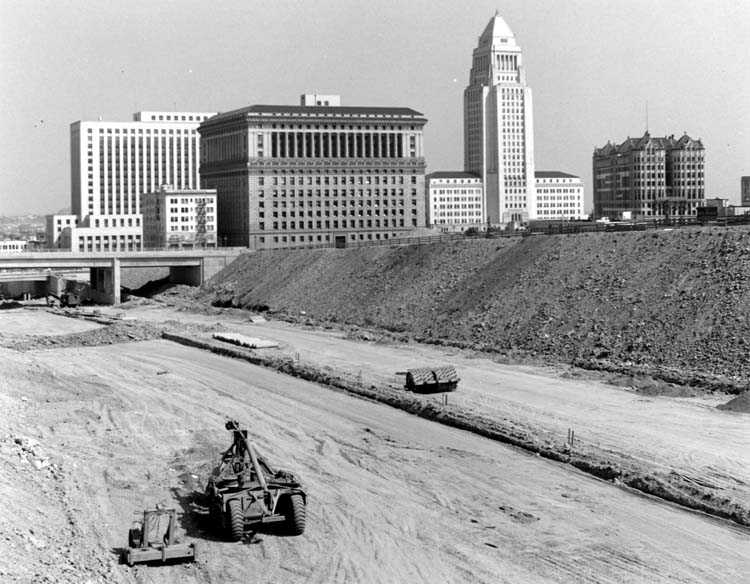 This photo shows a highway under construction with several buildings in the background.